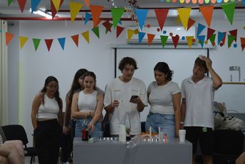 Fünf junge Menschen stehen an einem rituell gedeckten Tisch und halten eine Shabbat-Zeremonie ab.