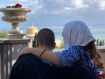 Ein Mann und eine Frau stehen mit dem Rücken zur Kamera, blicken auf Haifa und halten sich in den Armen