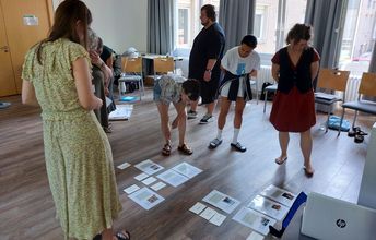 Teilnehmende betrachten auf dem Boden liegende Blätter Papier.