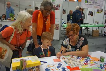 Besucher*innen stehen am ConAct Stand und lassen sich das hebräische Alphabet erklären.