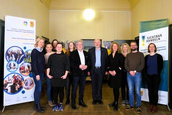 Besuch_Privorozki_Schneiß Gruppe von Menschen steht gemeinsam im Flur und schaut in die Kamera