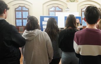 Gruppe junger Menschen hört jemandem zu. (Rückenansicht)