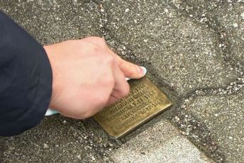Ein Stolperstein wird geputzt.