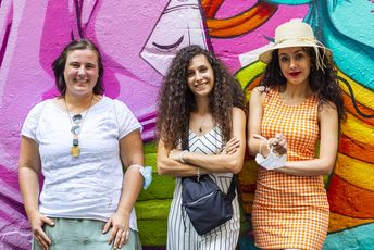 Drei junge Frauen posieren vor bunter Street Art