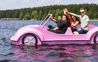Vier Teilnehmende einer Deutsch-Israelischen Jugendbegegnung sitzen zusammen in einem Tretboot in Form eines rosa Autos.