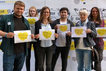 Aktuer*Innen der Internationalen Jugendarbeit halten ihre Forderungen auf Schildern hoch.