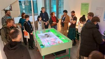 Eine Personengruppe steht um einen interaktiven Tisch herum