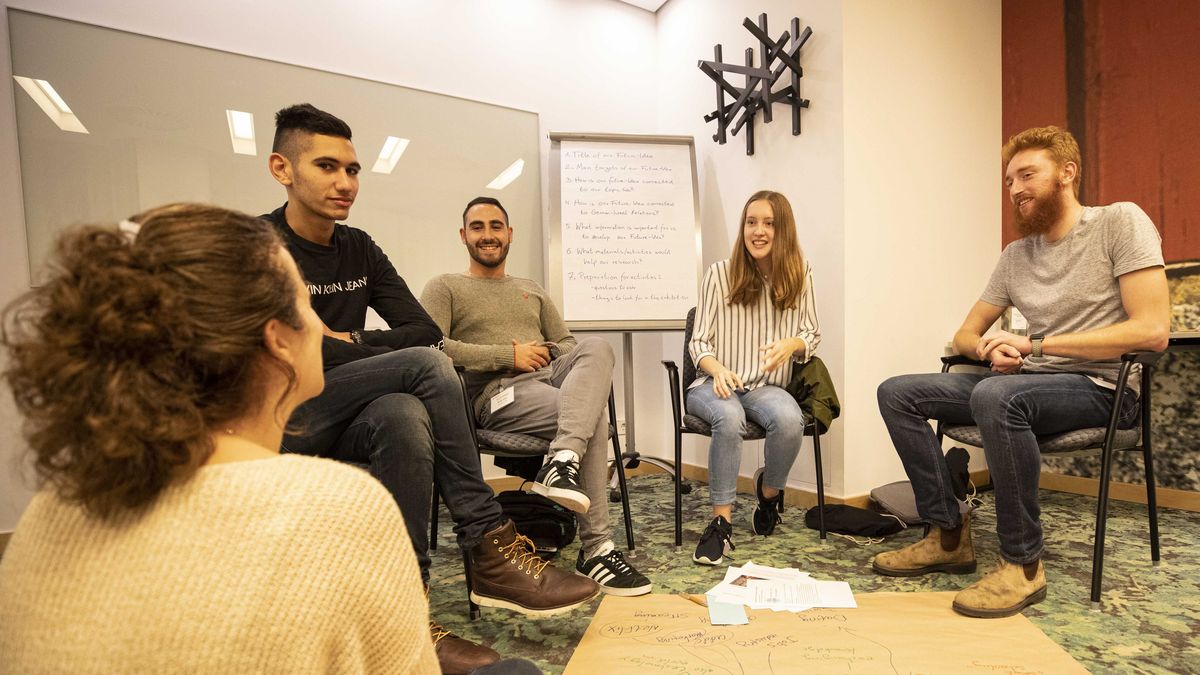 Mehrere junge Menschen sitzen zusammen und besprechen etwas