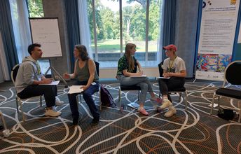 Vier Teilneh,mende sitzen sich jeweills zu zweit gegenüber und unterhalten sich.