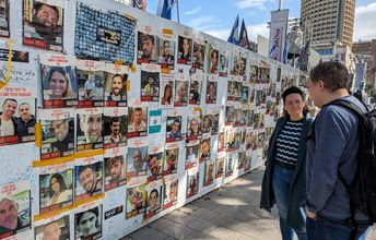 An einer Weißen Wand hängen Bilder und entführten und vermissten Menschen.