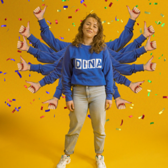 Eine Frau mit vielen Händen trägt einen Pulli auf dem "DINA" steht