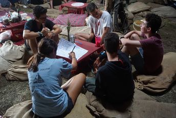 Erste Schreibübungen auf Hebräisch. (Foto © ConAct) Eine Gruppe von Jugendlichen sitzt zusammen um einen Tisch und schreiben auf ein Papier.