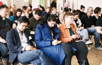 Drei Teilnehmende schreiben konzentriert auf Papier