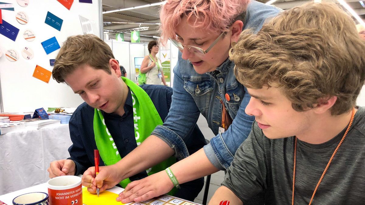 Eine Frau und zwei Jugendliche an einem ConAct-Infostand