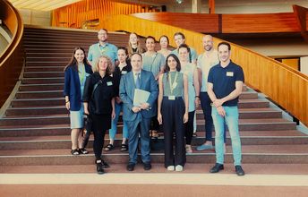 Foto einer repräsentativen Gruppe, die auf einer geschwungenen Treppe steht.