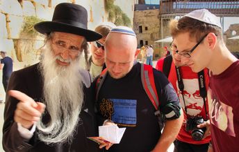 Eine Gruppe von Jugendlichen im Gespräch mit einem alten Mann.