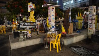 Auf einem öffentlichen Platz stehen gelbe Stühle und ein Klavier. Überall sind Fotos der Geiseln angebracht.