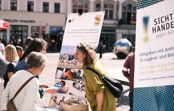 Eine Frau unterhält sich mit zwei anderen.
