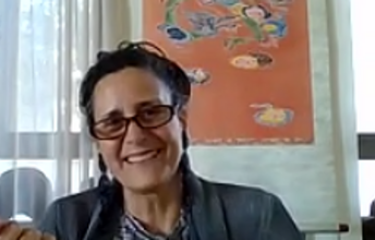 Frau mit Brille lächelt in Kamera und redet