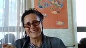 Frau mit Brille lächelt in Kamera und redet