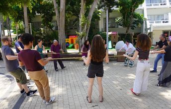 Personen stehen im Kreis und halten sich alle an einem Seil fest