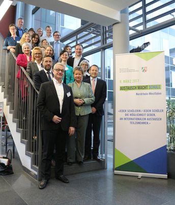 Auf einer Treppe stehen Menschen und gucken in die Kamera; Gruppenfoto