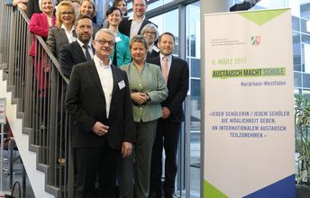 Auf einer Treppe stehen Menschen und gucken in die Kamera; Gruppenfoto