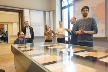 Die Teilnhemenden hören dem Führer im Haus der Wannseekonferenz zu, der gerade etwas erklärt.