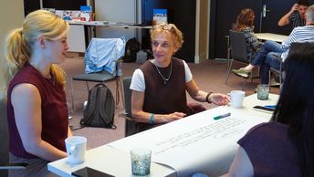 Zwei Frauen sitzen an einem Tisch und reden miteinander