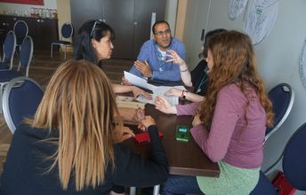 Fünf Teilnehmende sitzen an einem Tische und diskutieren.