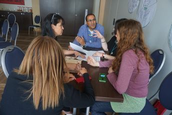 Fünf Teilnehmende sitzen an einem Tische und diskutieren.