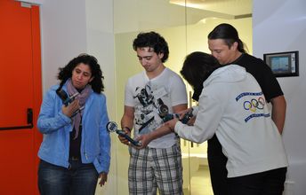 Drei Personen stehen in einem Museum mit verschiedenen Geräten in der Hand nebeneinander