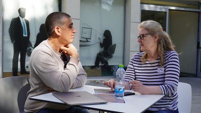 Zwei Menschen stehen an einem Stehtisch und unterhalten sich angeregt.