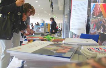 Besucher und Besucherinnen schauen sich Infomaterial von ConAct an