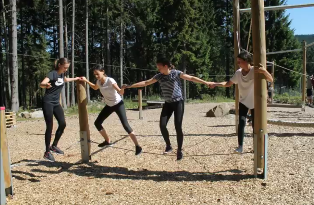 Vier junge Menschen balancieren auf einem Seil.