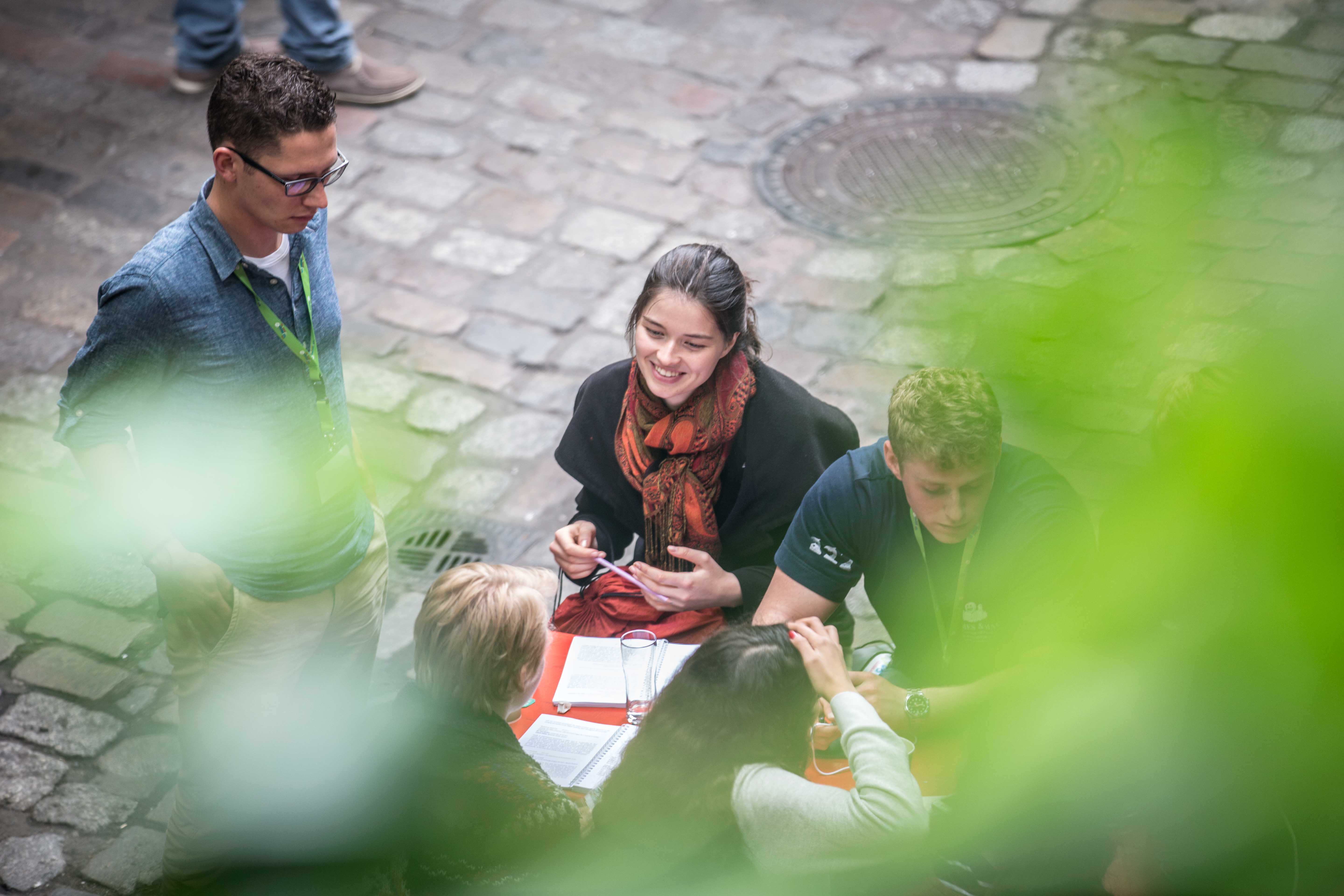 Eine junge Frau sitzt mit anderen Jugendlichen am Tisch