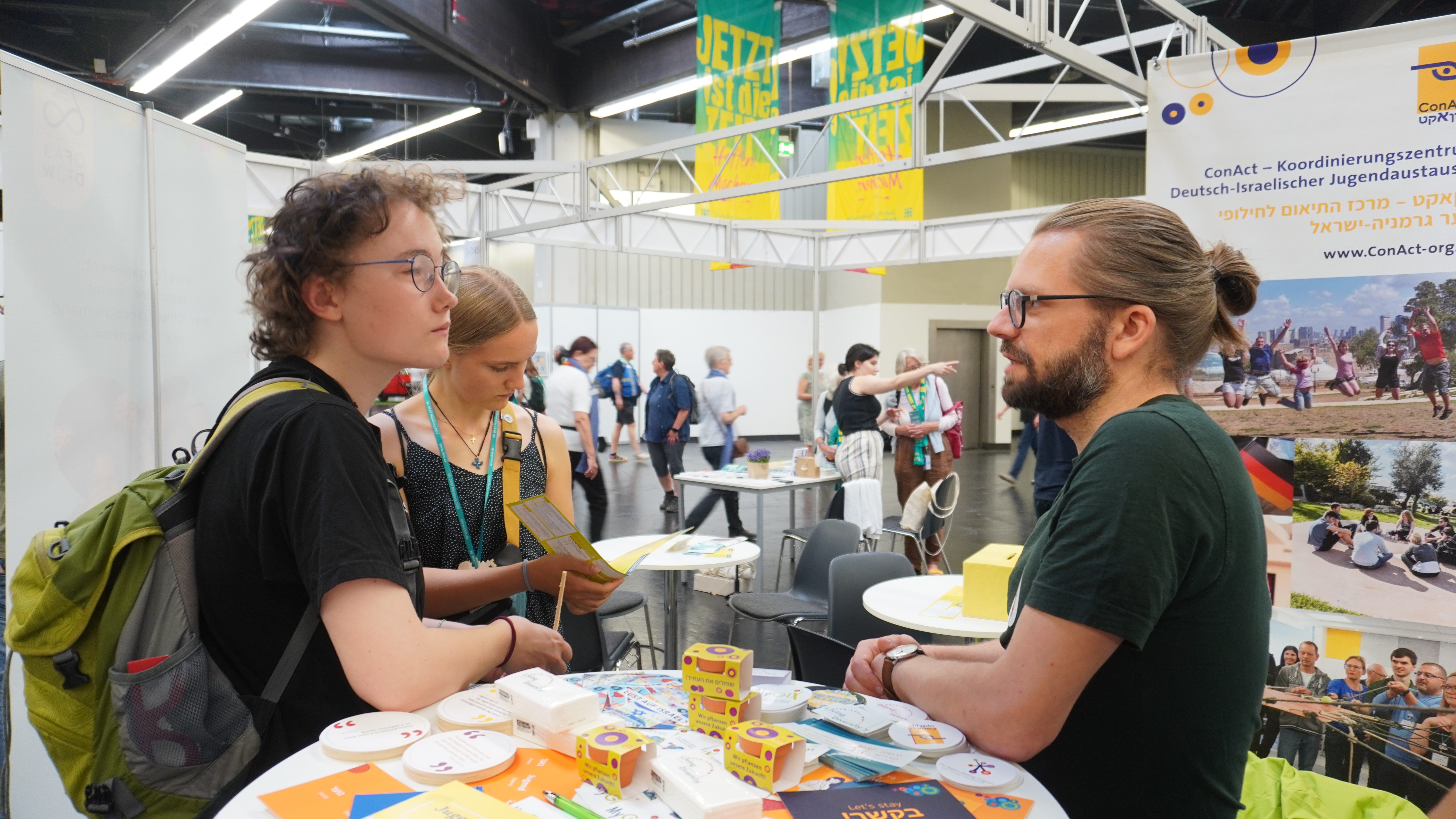 Ein ConAct-Mitarbeiter im Gespräch mit zwei Jugendlichen über den deutsch-israelischen Jugendaustausch
