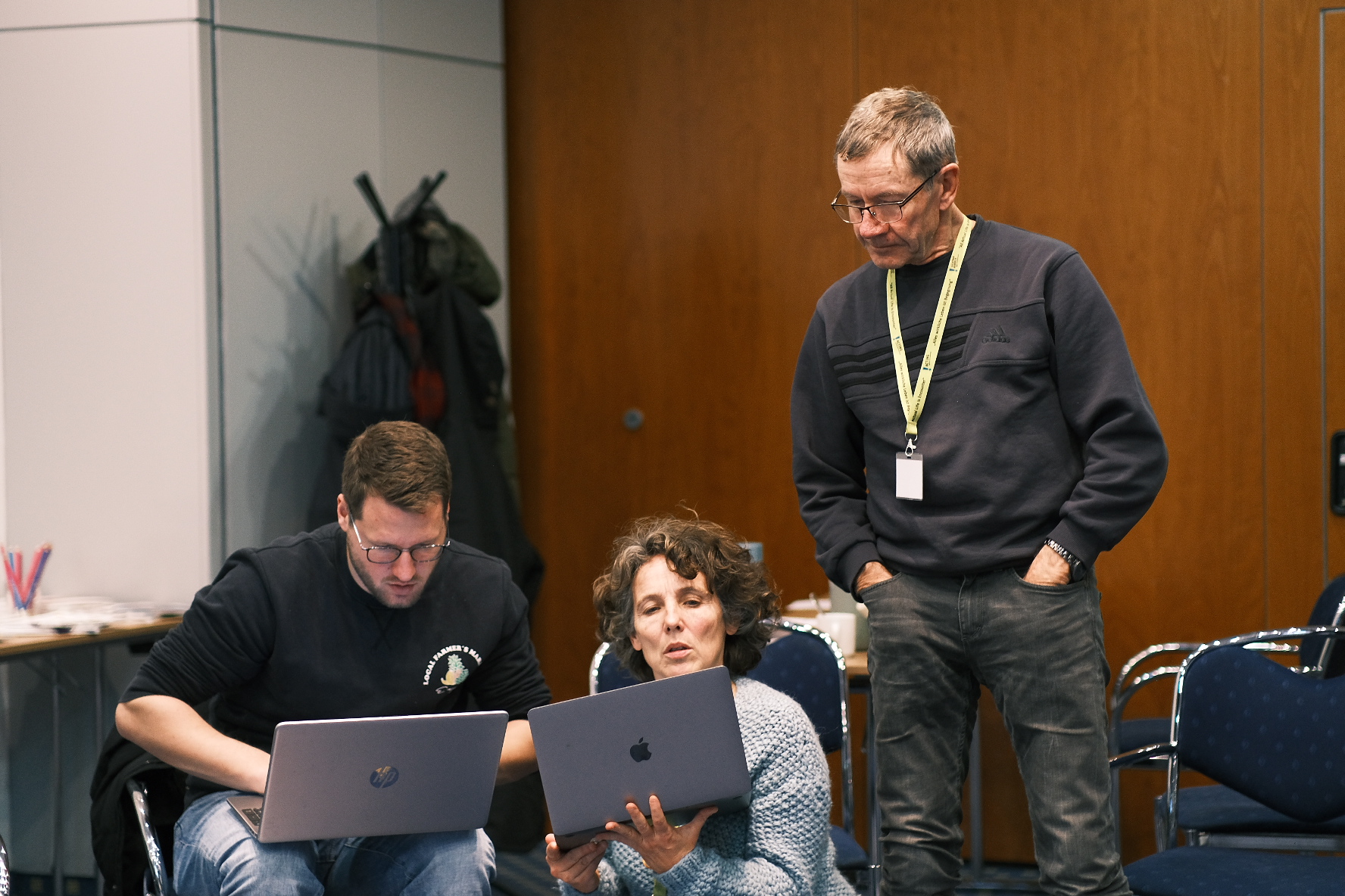 Kleingruppe berät sich an Laptops sitzend.