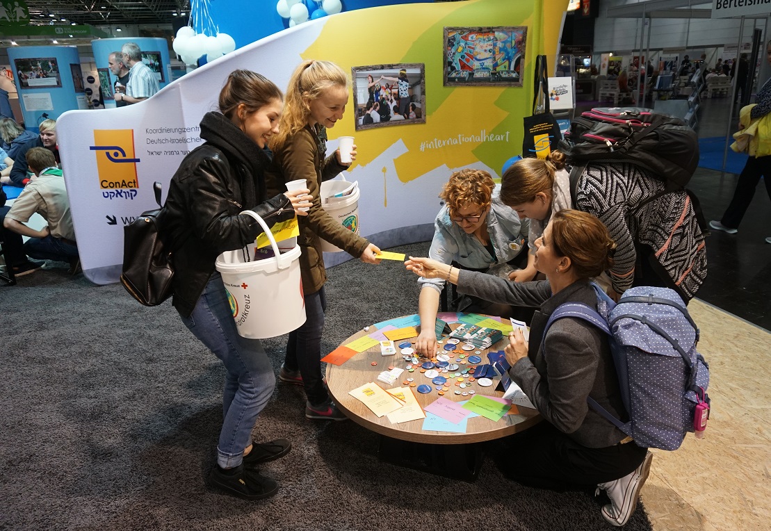 Junge Frauen informieren sich an einem ConAct-Messestand auf dem Deutschen Jugendhilfetag