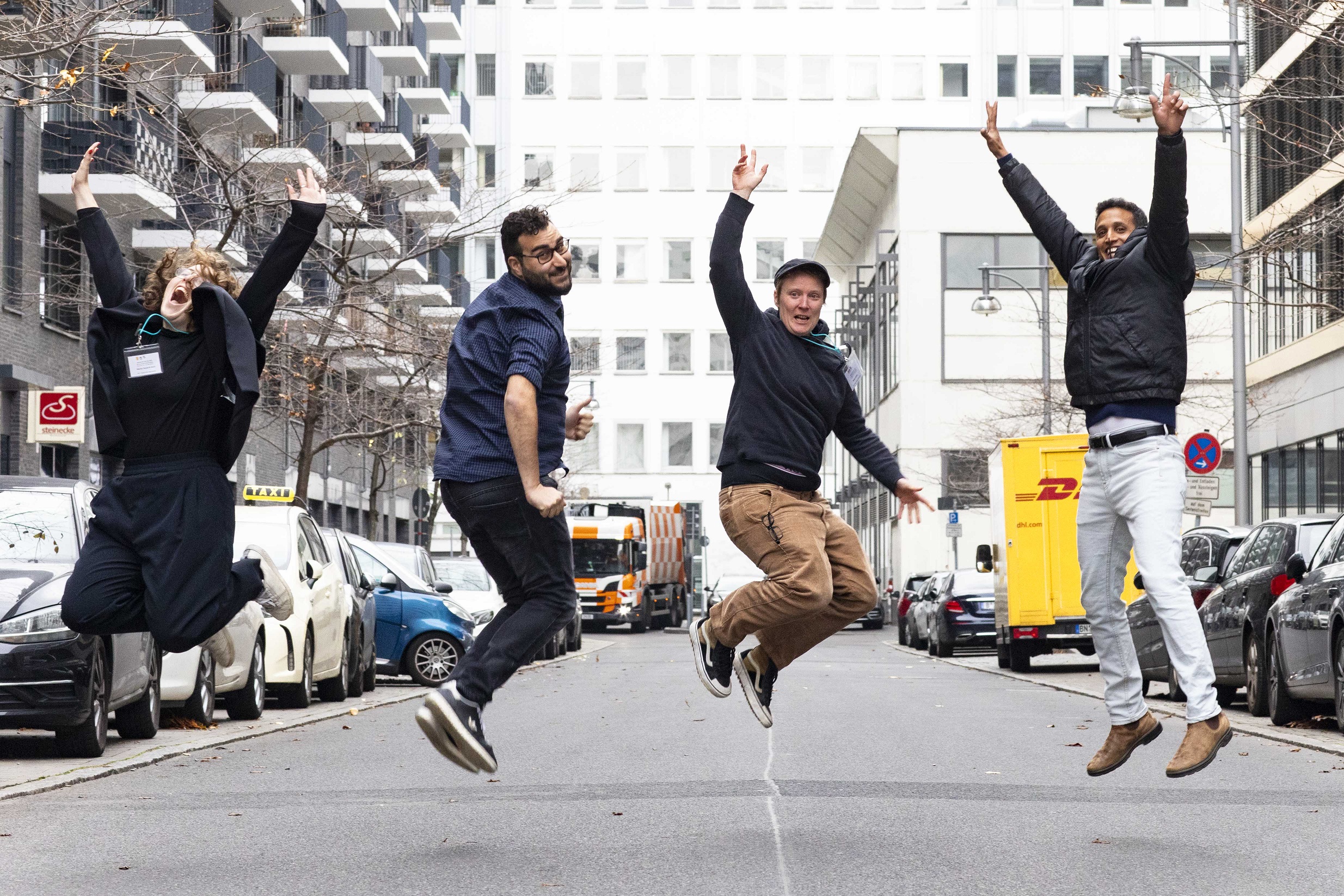 Vier Menschen springen auf einer Straße in Berlin in die Luft